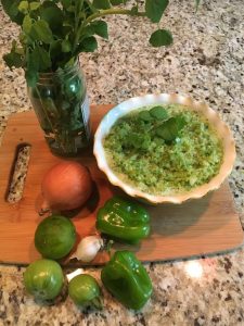 Photo of ingredients for salsa verde, including green tomatoes, green bell peppers, onions, garlic, lime and papalo with a bowl of prepared salsa verde. https://trimazing.com/ 