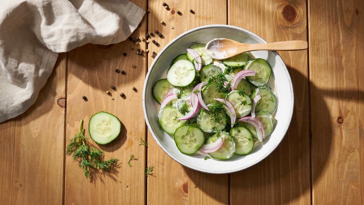 Fresh cucumber dill yogurt salad in white bowl with red onion slices.