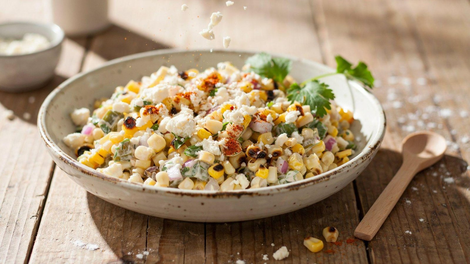 Cotija cheese and smoky spices sprinkled over creamy healthy Mexican street corn salad before serving.