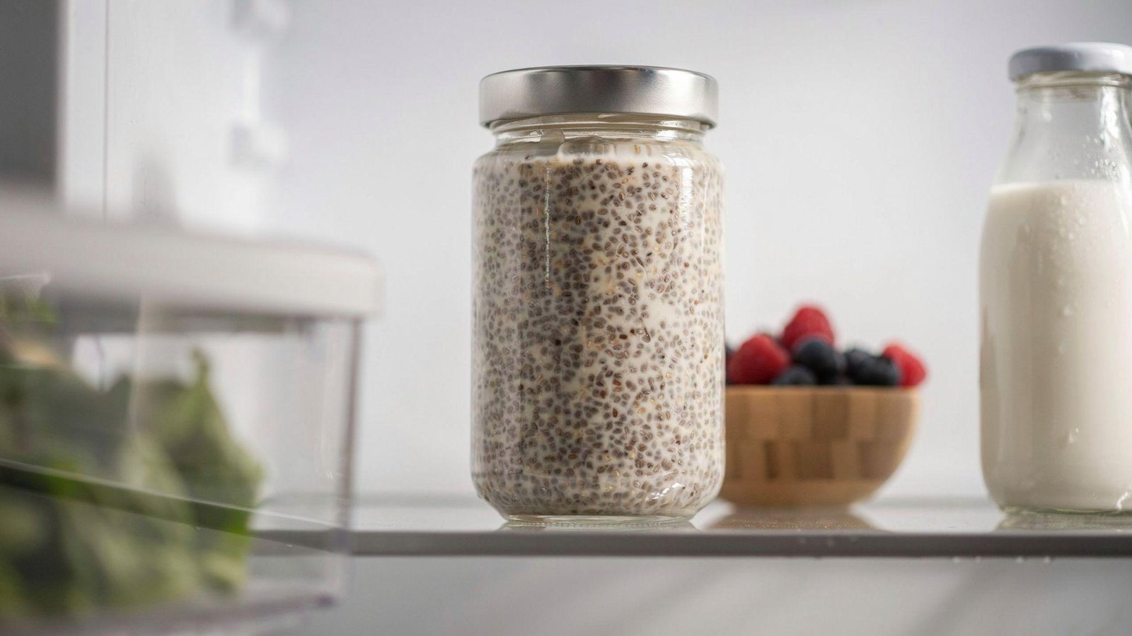 Glass jar of chia pudding chilling in refrigerator until thick, creamy, and ready to enjoy.