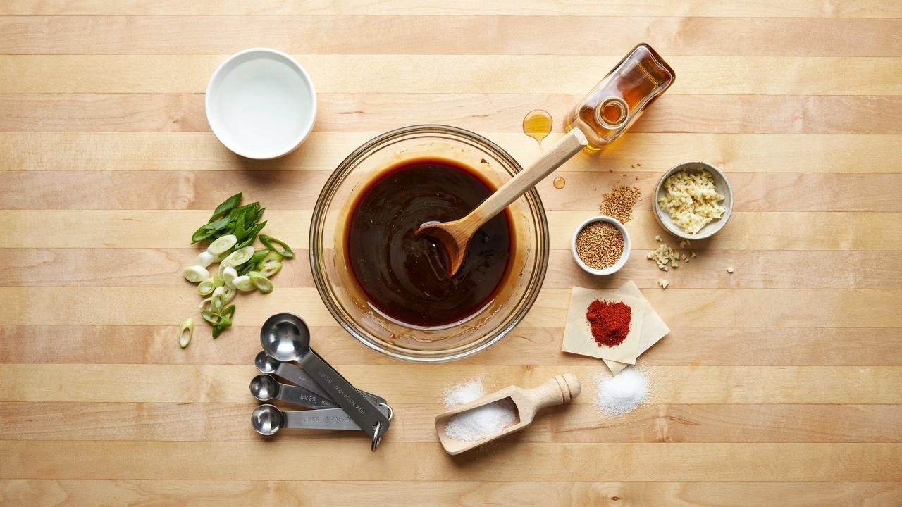 Soy sauce marinade being mixed with garlic, green onions, sesame seeds, and seasonings.