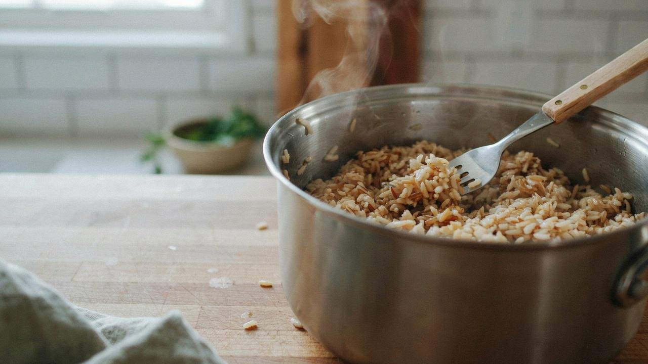 Fluffy brown basmati rice being gently fluffed with a fork before serving.