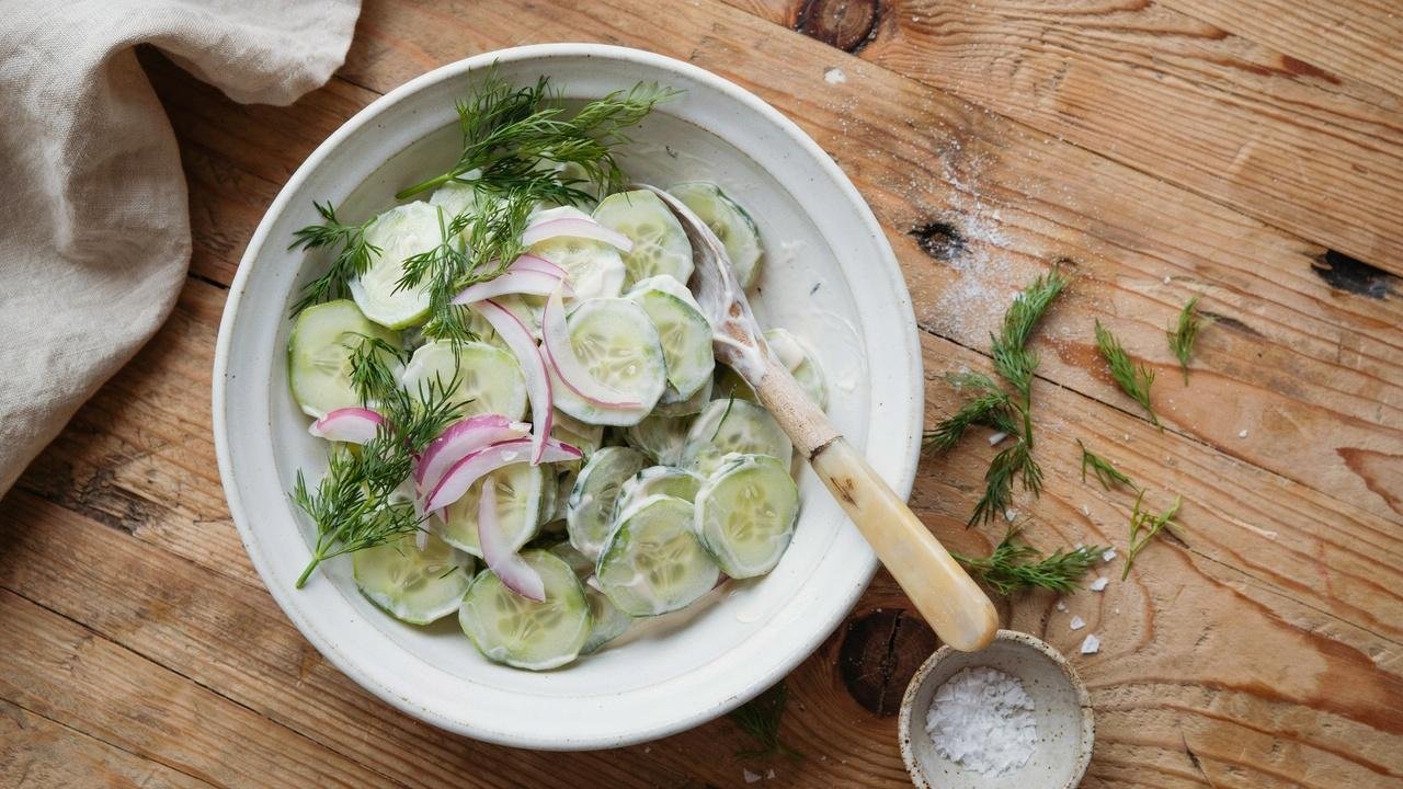 Overhead shot of the creamy cucumber dill yogurt salad in a white ceramic bowl.