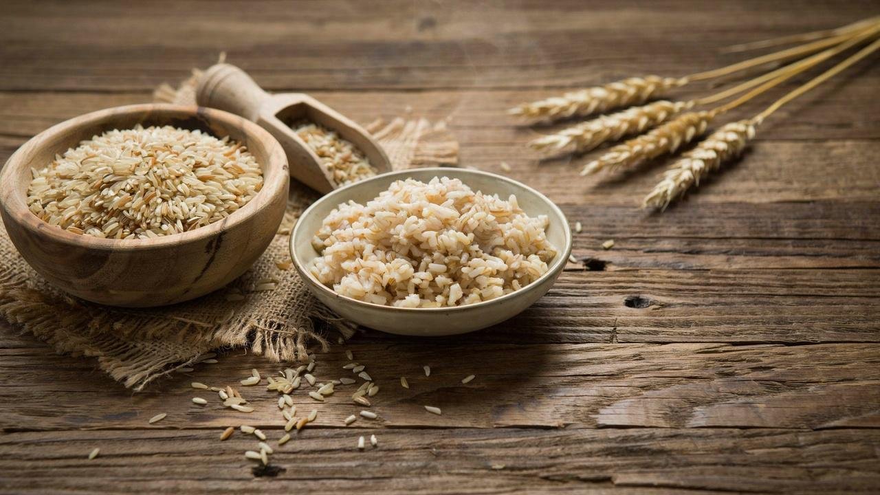 Brown basmati rice shown uncooked and cooked side by side, highlighting its long grains and fluffy texture in a rustic setting.