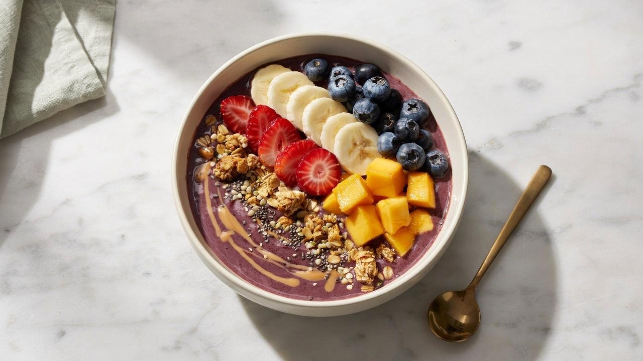 Vegan acai bowl topped with fresh fruits, granola, seeds, and a nut butter drizzle.