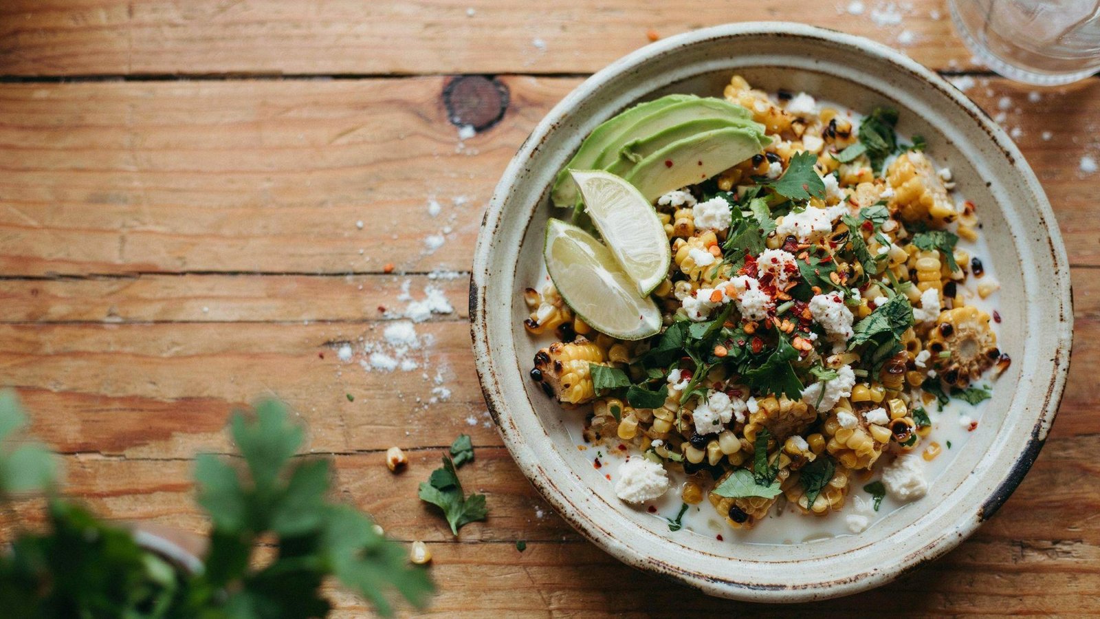 Fresh healthy Mexican street corn salad with grilled corn, cilantro, cotija, lime, avocado, and light creamy dressing
