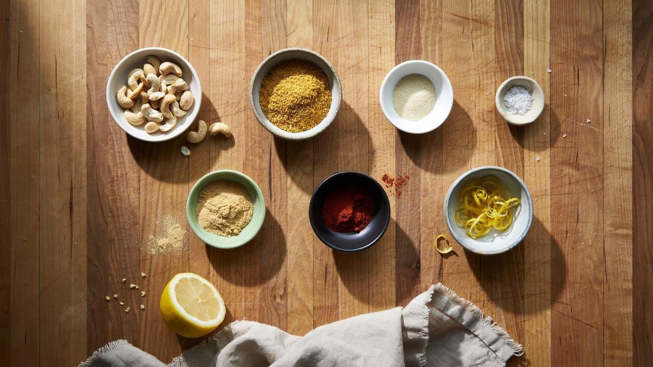 Simple ingredients for cashew parmesan including raw cashews, nutritional yeast, garlic powder, and seasonings.
