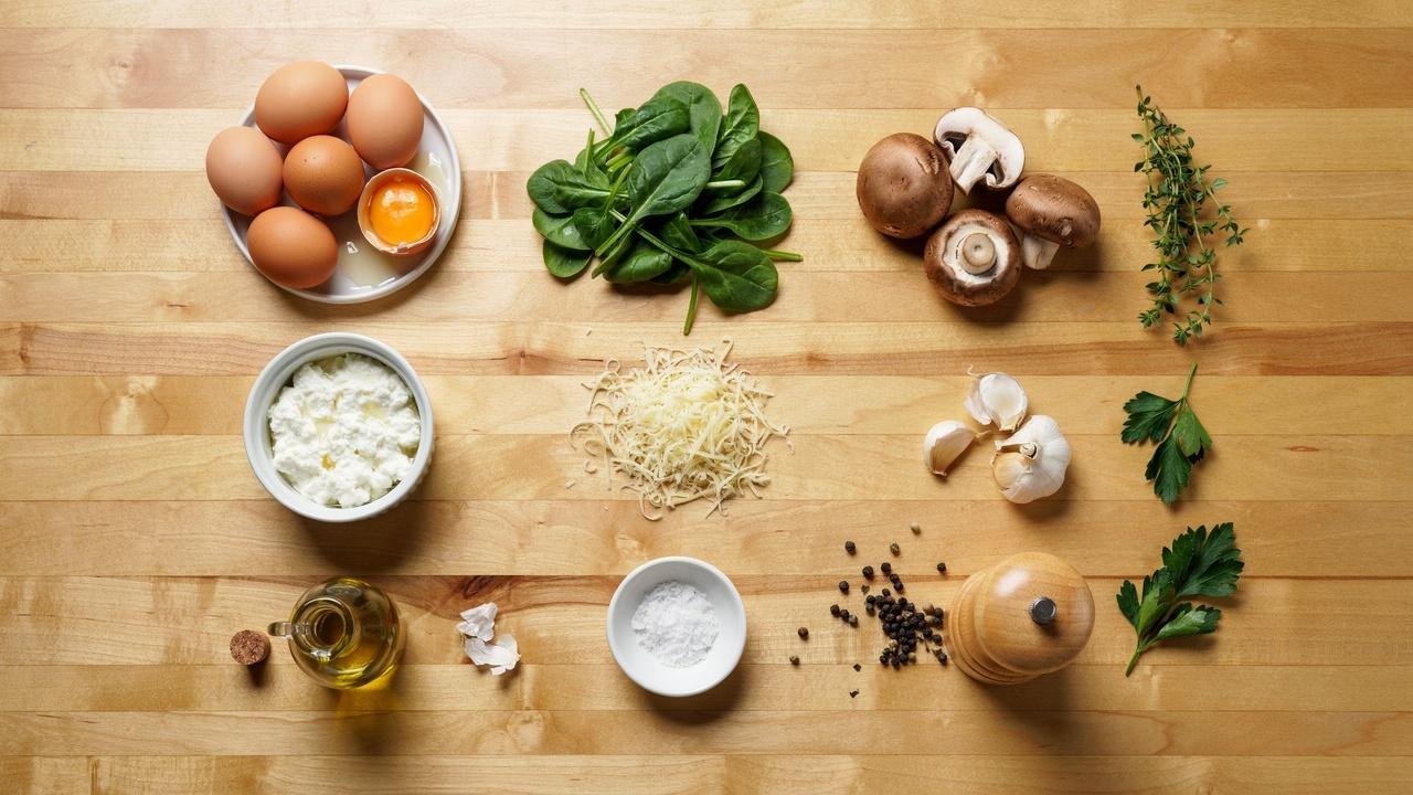 Ingredients for spinach mushroom egg bites including eggs, spinach, mushrooms, cottage cheese, Swiss cheese, garlic, and olive oil.