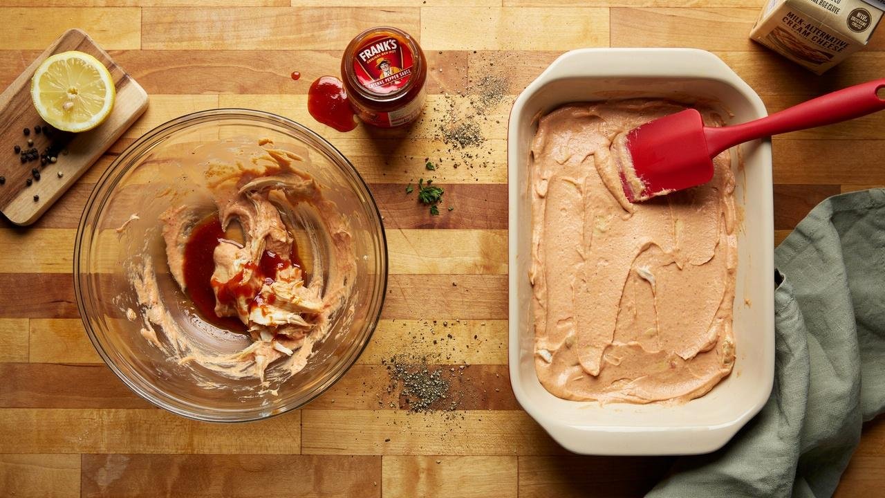 Buffalo chicken dip mixture spread evenly into a baking dish before baking.