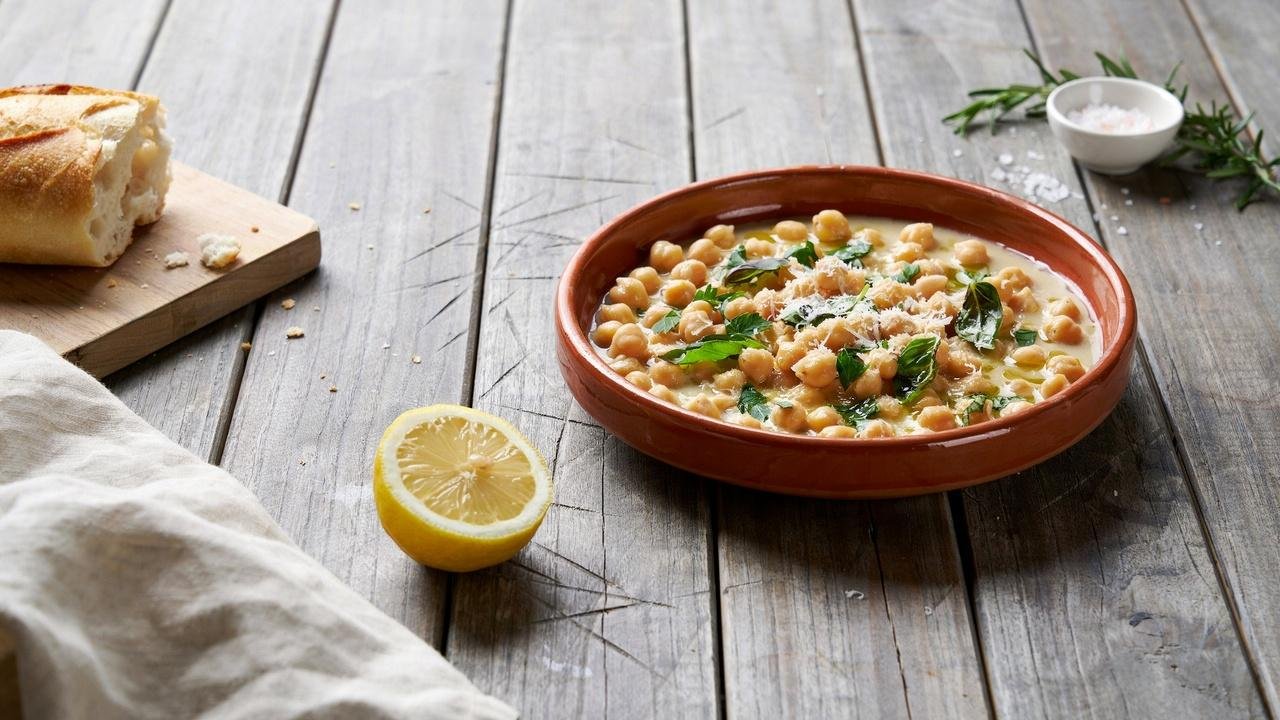 Creamy Tuscan chickpeas topped with Parmesan and lemon, served hot with crusty bread for a comforting meal.
