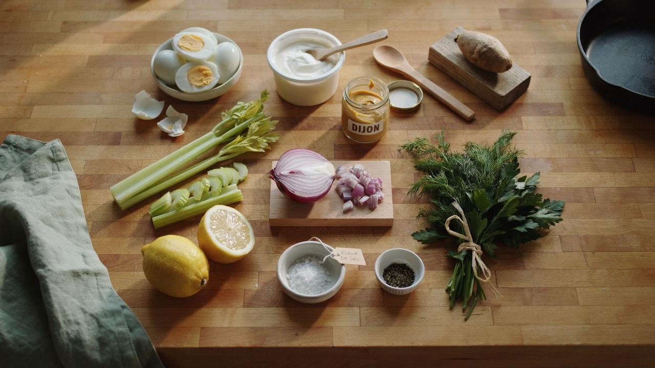 Ingredients for high protein egg salad including eggs, Greek yogurt, mustard, celery, herbs, and lemon.