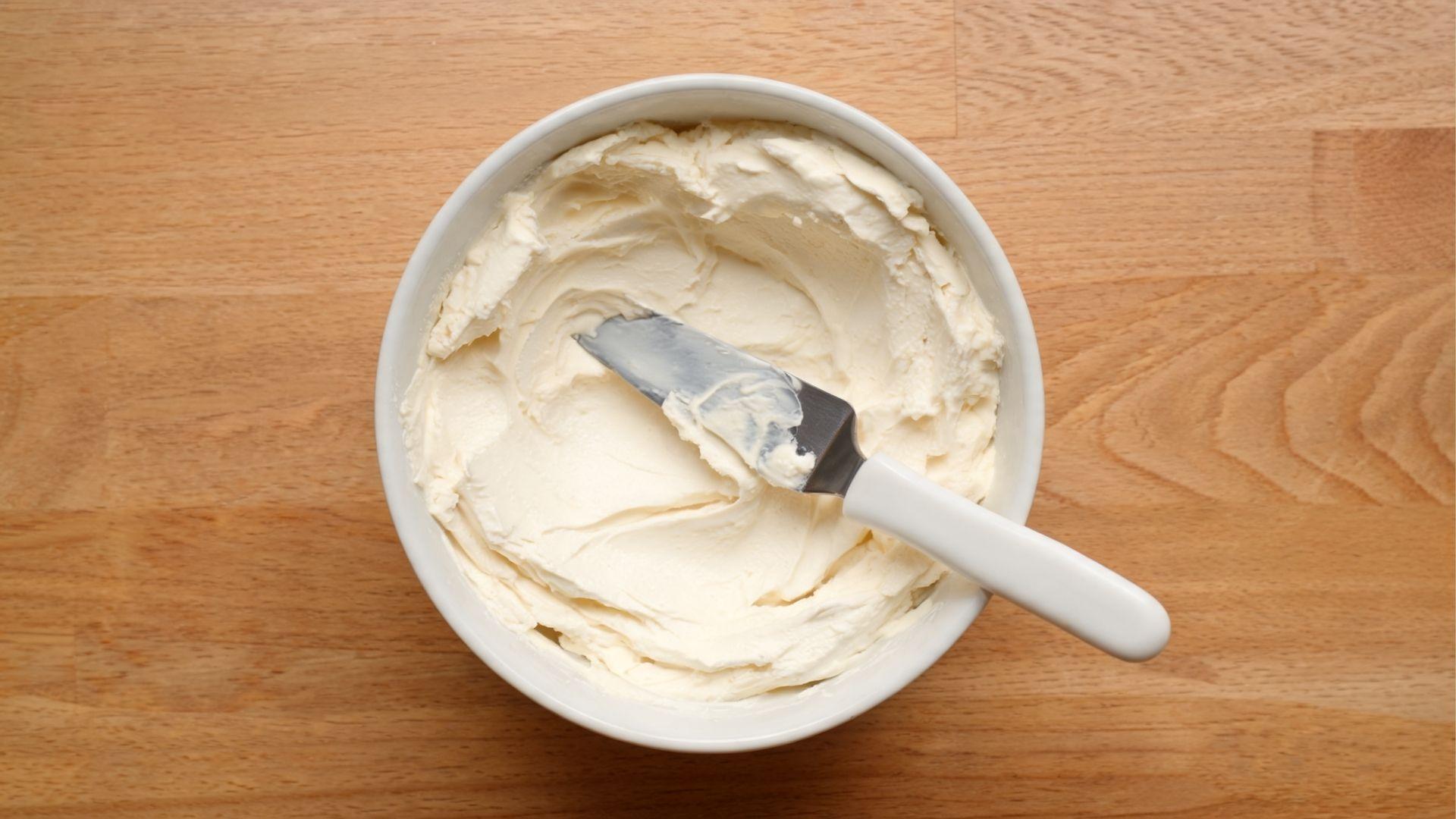 Cream cheese frosting in a bowl with a small offset spatula