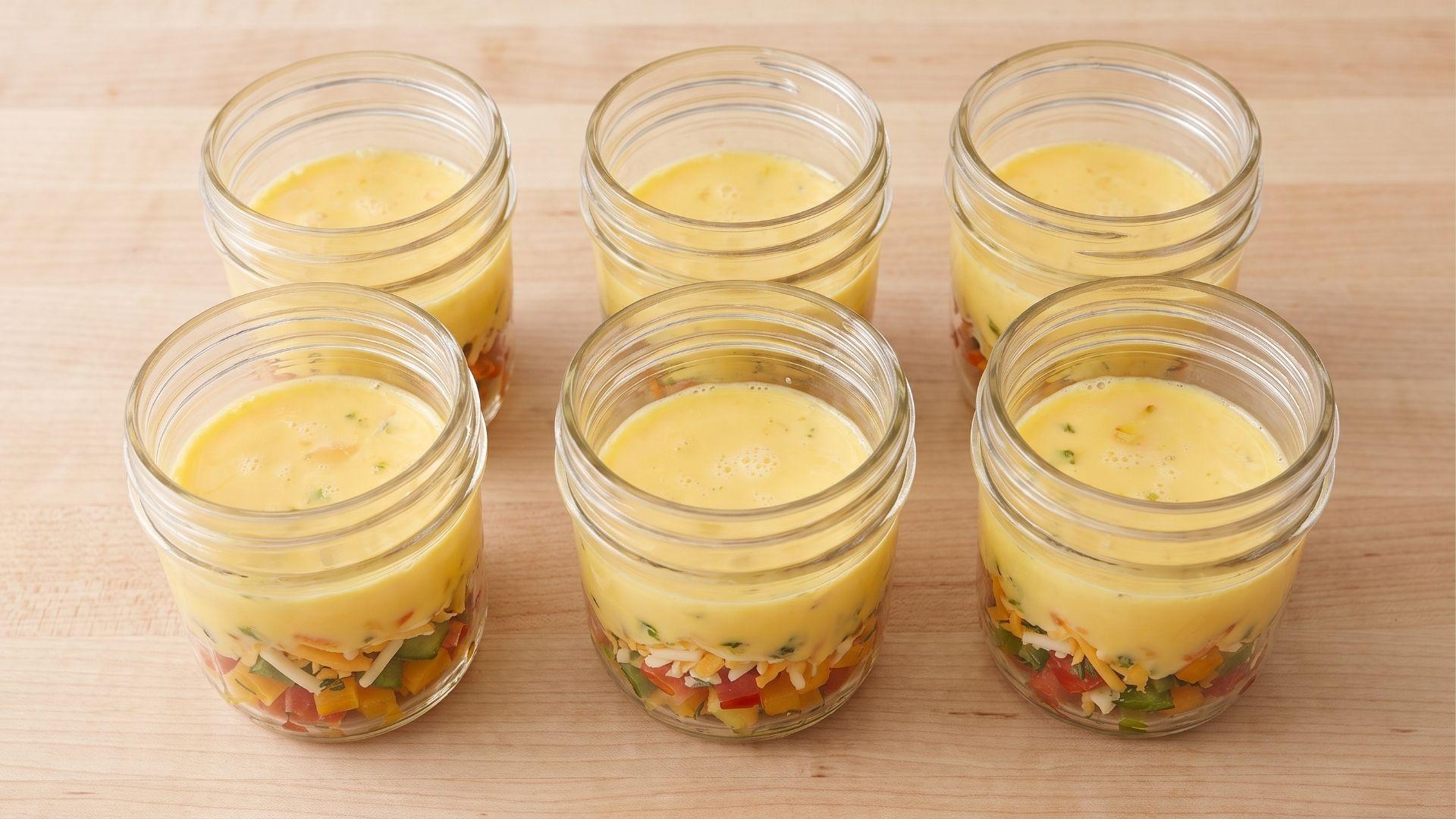 Small jars filled with mix-ins and egg mixture with space at the top