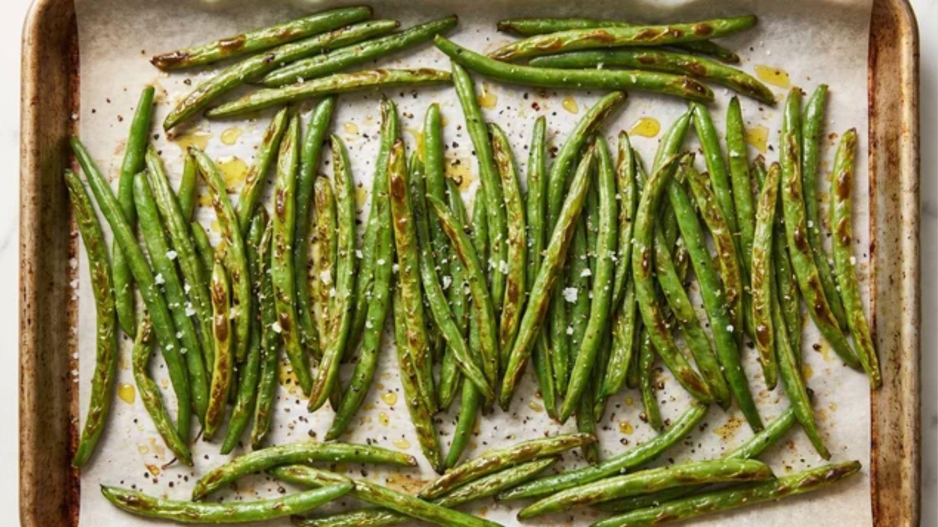 Roasted green beans in the oven with golden, blistered edges on a baking sheet