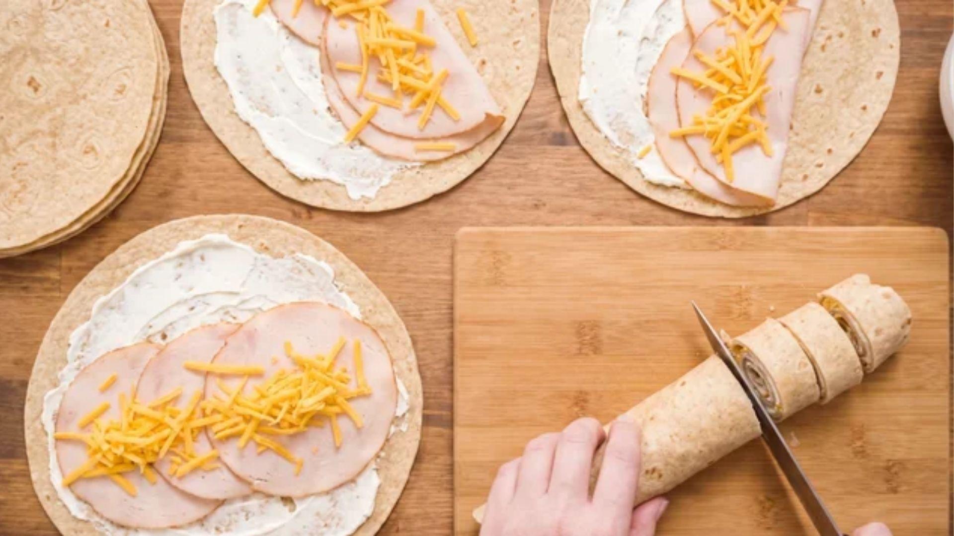 Low carb tortillas layered with cream cheese, turkey, and shredded cheddar
