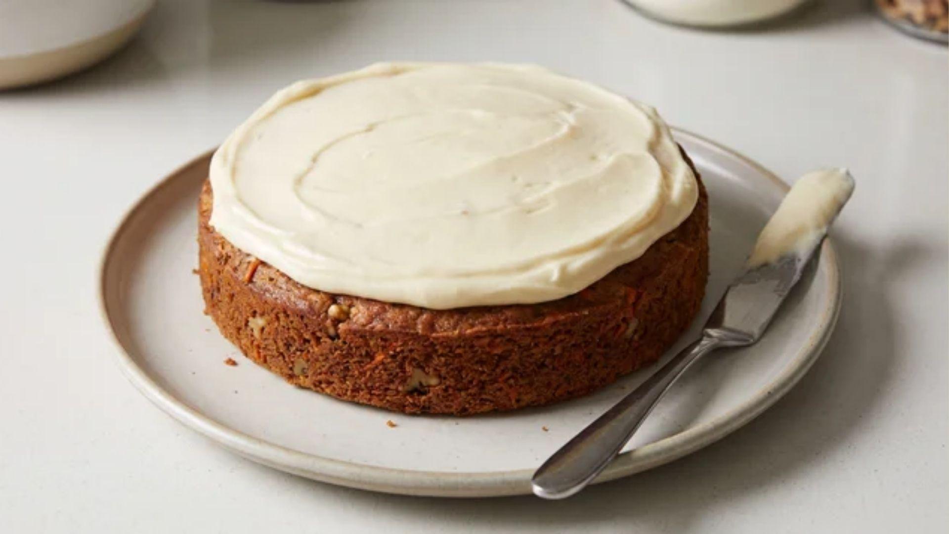 Cream cheese frosting spread over the top of a small carrot cake