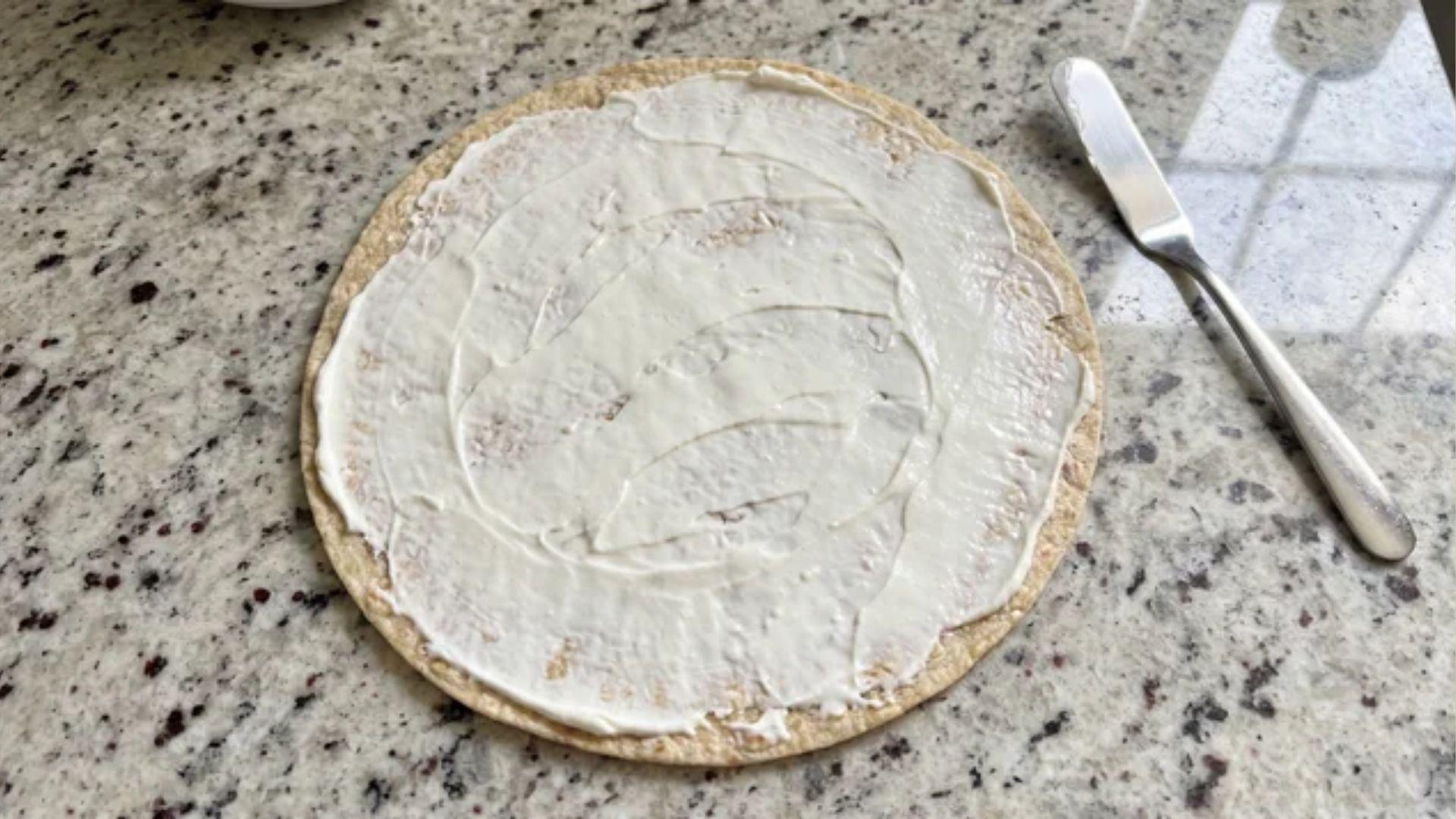 Low carb tortilla covered with an even layer of cream cheese
